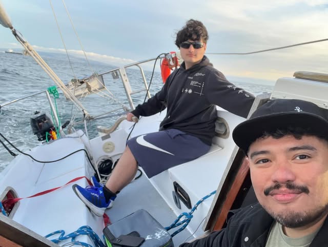 Two people aboard a sailboat on open water